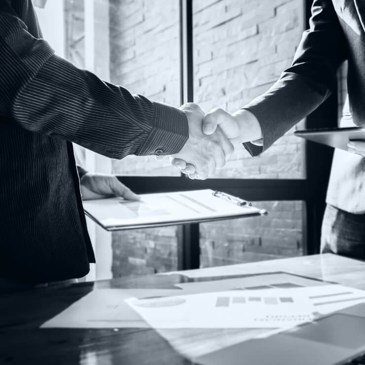 Two people shaking hands over charts