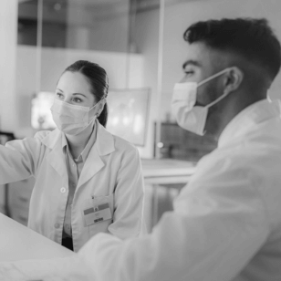 Two masked doctors looking at a screen together