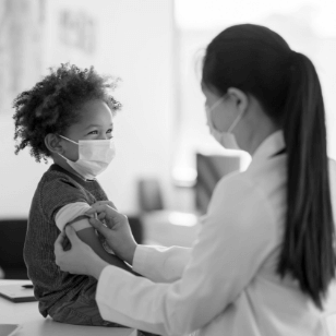 Female doctor placing a bandaid on a child's arm